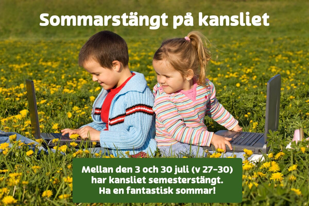 Barn med datorer i gräset.